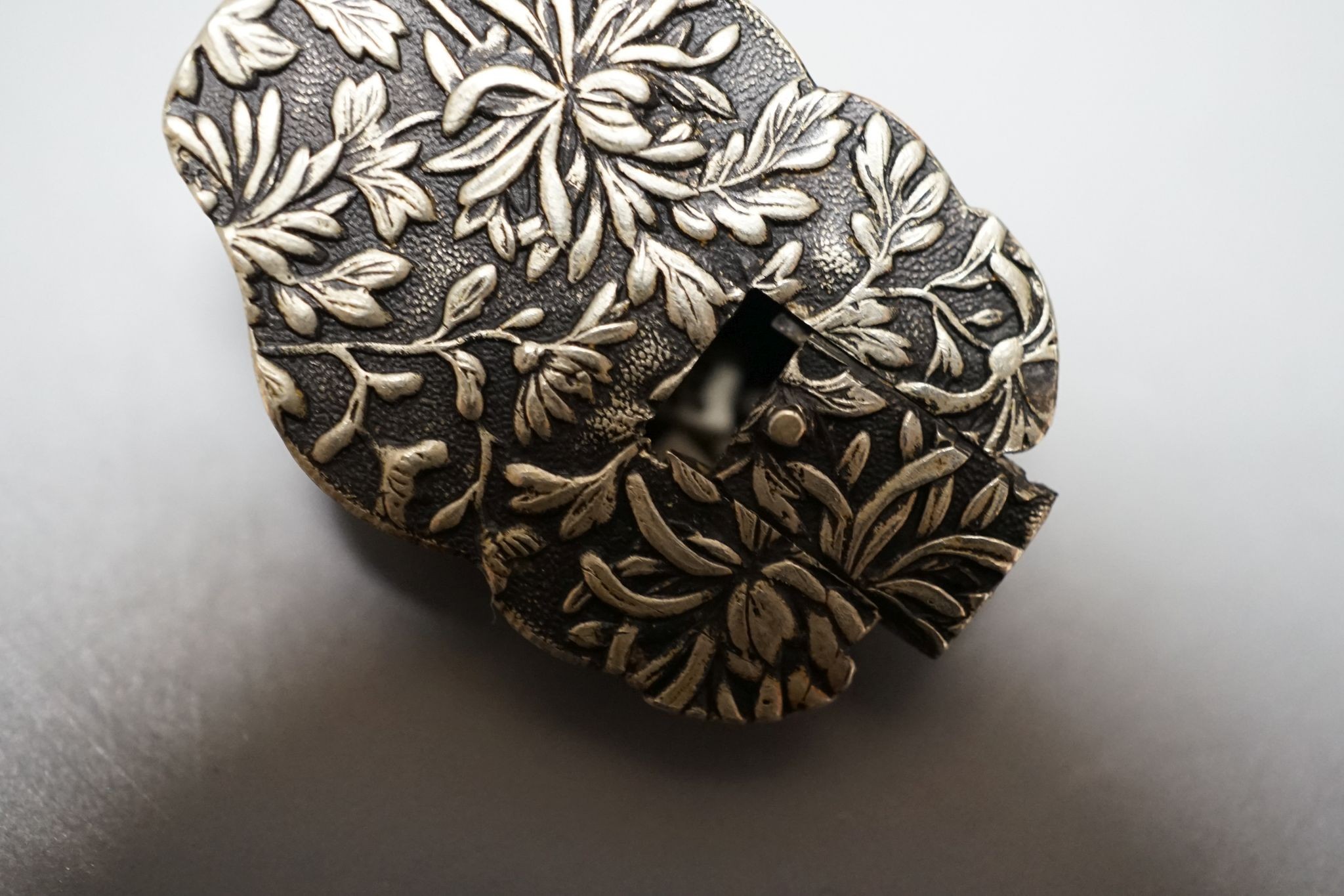 An unusual Japanese mixed metal noh mask containing minute bone dice and a stag antler noh mask brooch, signed, 3.5cm
